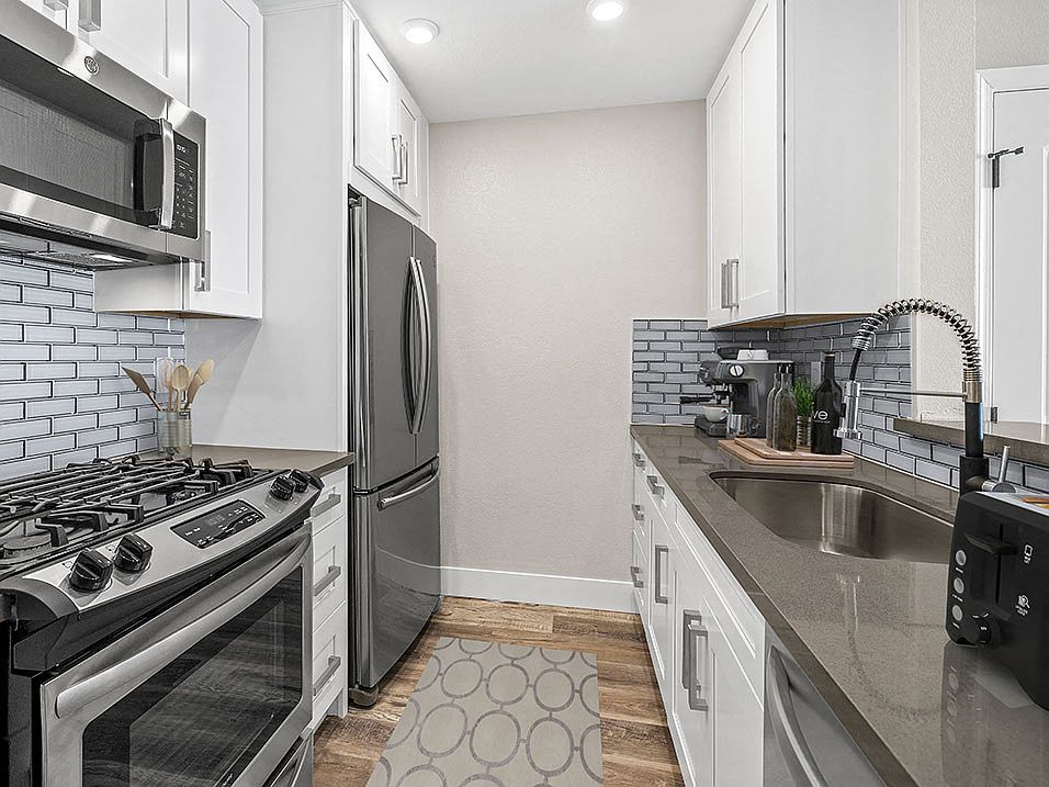 Blue tiled kitchen with stainless steel fridge, oven, and fixtures.