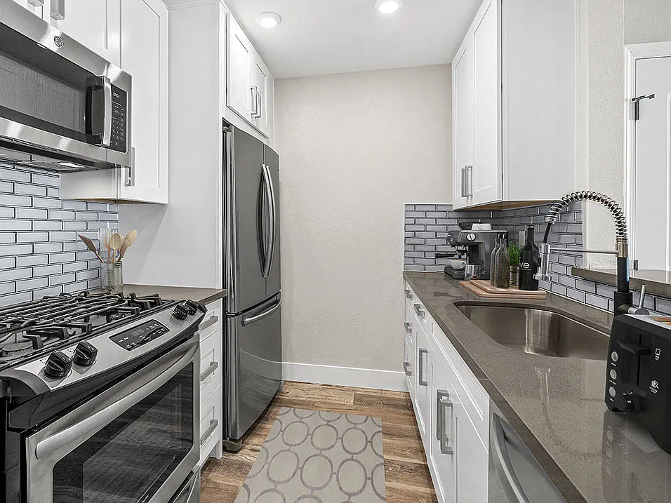 Blue tiled kitchen with stainless steel fridge, oven, and fixtures.