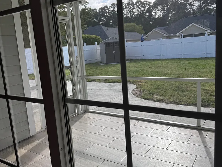 standing at back door looking out at screened porch to backyard.