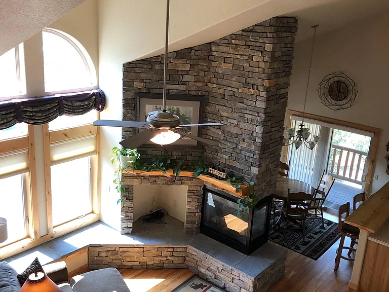 Sunny Great Room w/stone Fireplace Wall, Log Mantle, TV Alcove, and wrap-around stone Hearth. View l ooking down from Loft