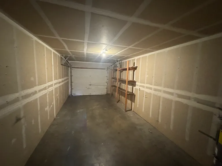 Spacious attached garage with built-in shelving for extra storage and everyday organization.