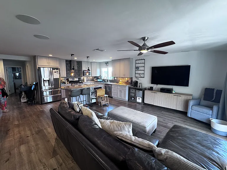 A large open concept living room, kitchen, dining, with sliding doors opening up to a spacious, covered deck.