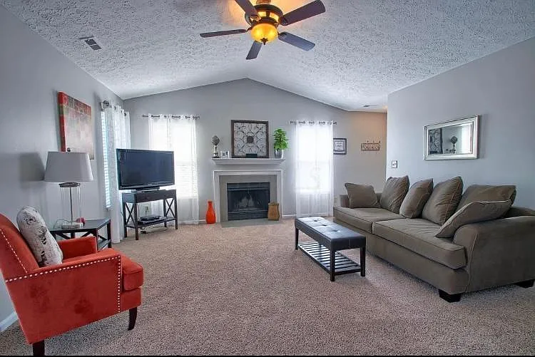 Spacious living room with vaulted ceilings, a brand new ceiling fan, wood burning fireplace, and plenty of natural light.