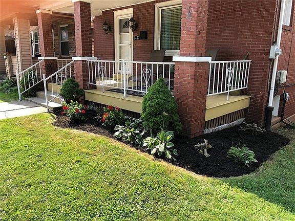 Front. Lush green grass contrasts nicely with the dark mulch. The current owner has lovingly maintained both the house and the y