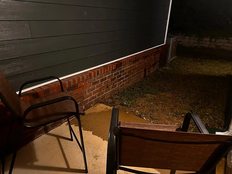 Small outdoor patio off the home with seating and a concrete pad for relaxing or enjoying fresh air.