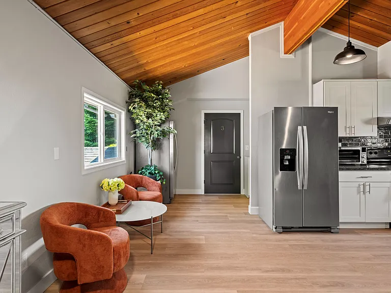Open-concept living area flows into the kitchen with stainless steel appliances, ample cabinetry, and vaulted wood ceilings.