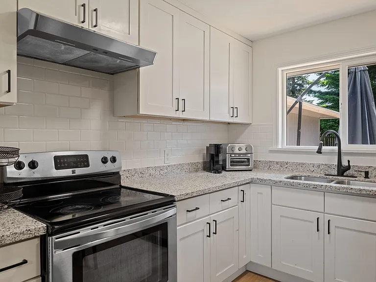 Updated kitchen with shaker cabinets, granite-look counters, stainless range, and a double-basin sink by the window.