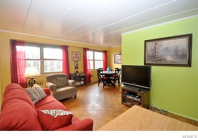 Spacious living room with large windows and a dining area.