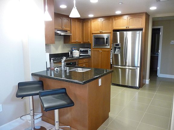 Kitchen with granite countertops; room for bar stools. Stainless steel refrigerator