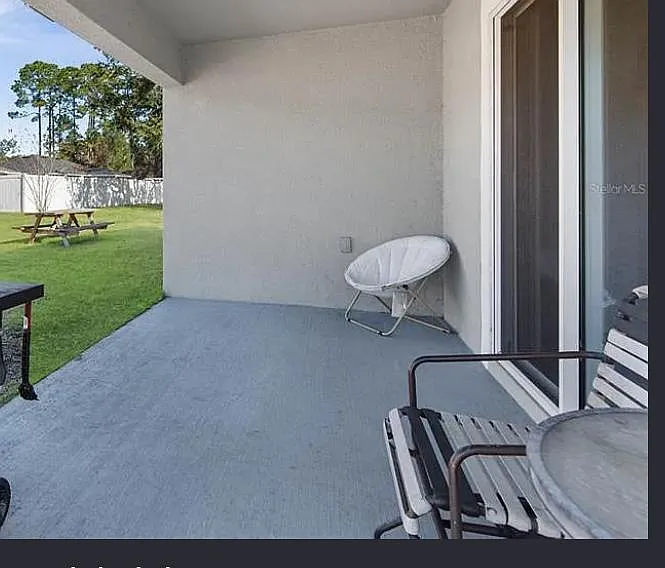 Covered patio with outdoor seating and sliding door access, opening to a spacious fenced backyard ideal for relaxing. - Ryken Ln