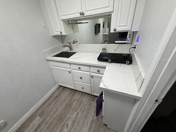 Kitchen with sink and quartz counter. Hotplate included.