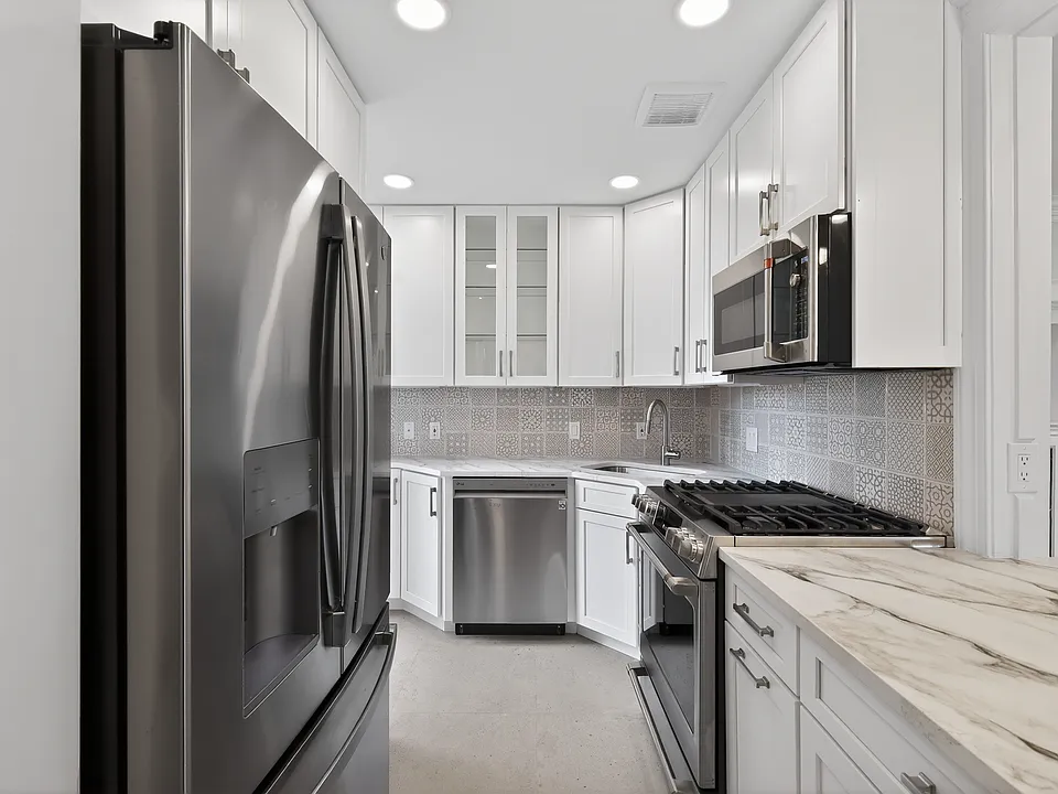 Kitchen featuring BRAND NEW top of the line GE Cafe range, oven and microwave. Island has a overhang for convenient meals. Tiles and backsplash are designer items from Porcelanosa.