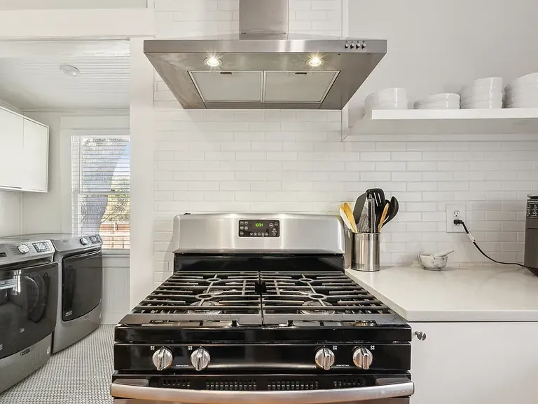Kitchen stove and view into laundry room which is now closed with a swinging door
