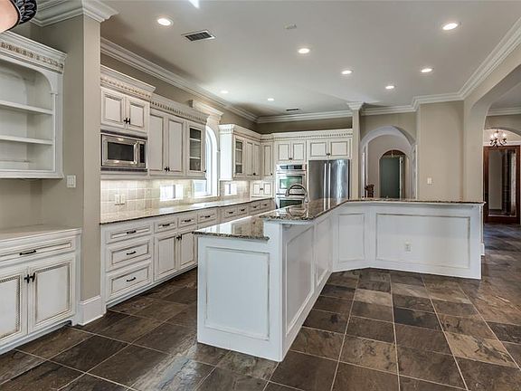 The Kitchen features Jenn-Air stainless steel appliances (refrigerator included!), granite counters and TONS of storage in custom cabinetry. Island has raised breakfast bar with space for barstools. Through center archway is spacious pantry and stora