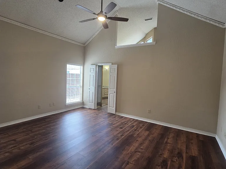 Master bedroom with high vaulted ceilings, modern ceiling fan and brand new wood flooring.