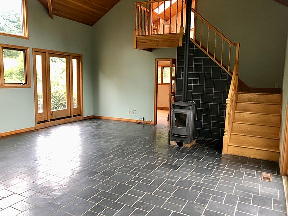 Living room with door leading outside to front deck. Door to left of pellet stove into bedroom. Stairs to office.