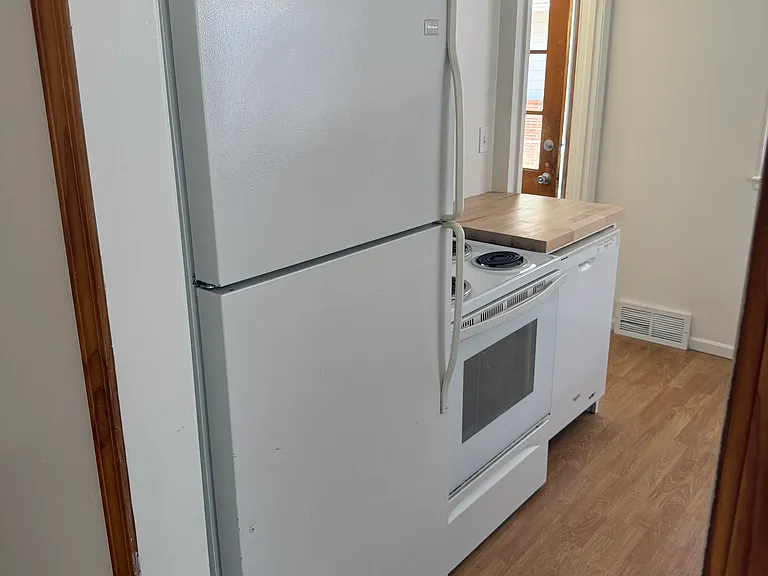 Newer white electric range refrigerator & built in dishwasher. View looking west to side entrance door off driveway