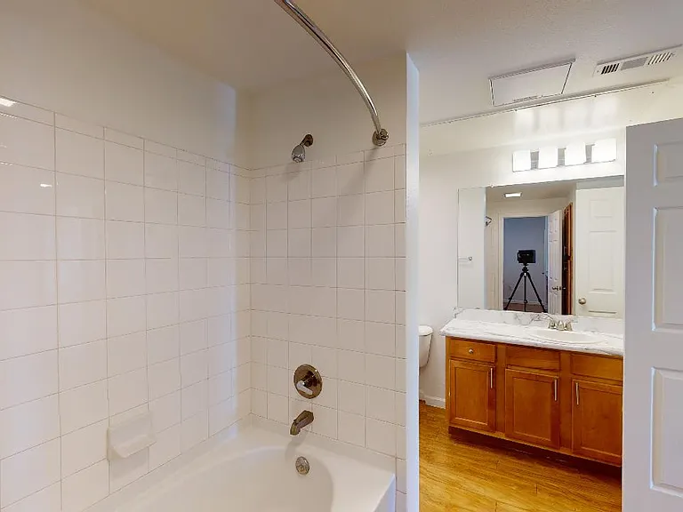 Apartment bathroom with wood-style flooring and marble-style countertops (shown here). Quartz-style countertops are available in select homes.