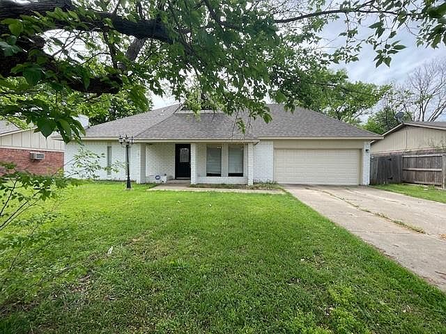Ranch-style home with fence, a garage, concrete driveway, a front yard, and brick siding