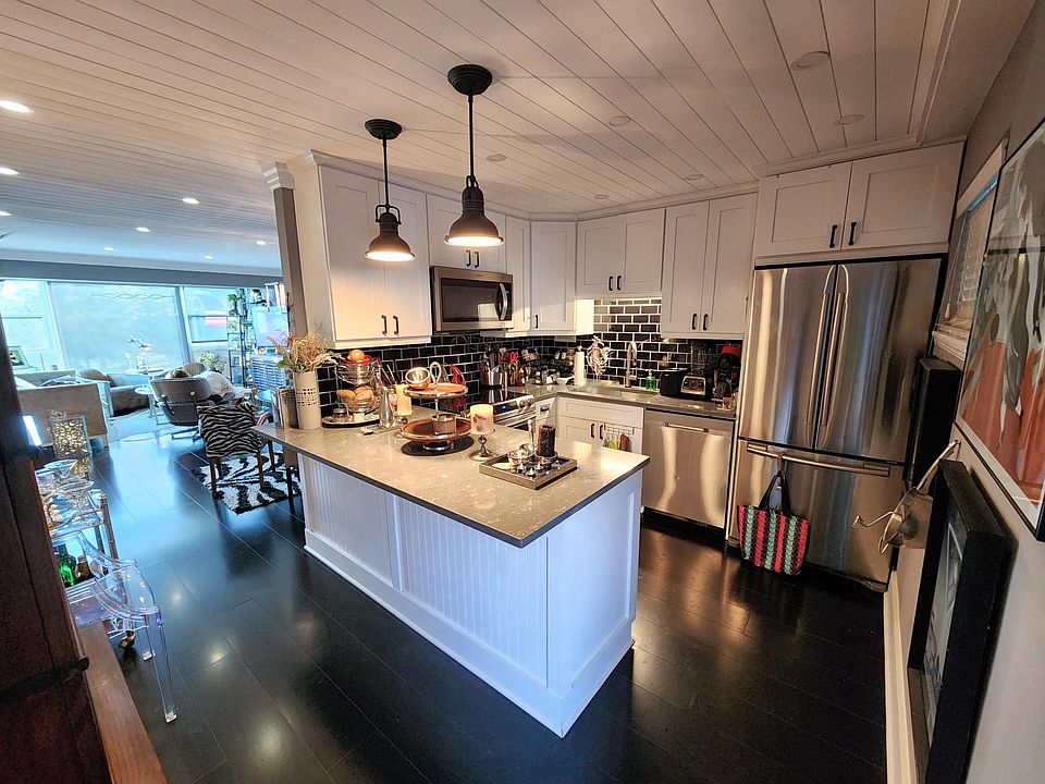 Entering the home, the beautifully appointed kitchen greets you in the foreground, while the fabulous living area beckons you from a distance.