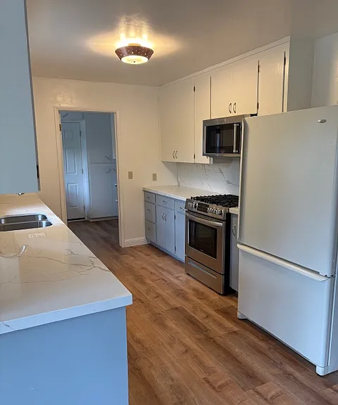 Kitchen with microwave, gas stove and oven, refrigerator.
