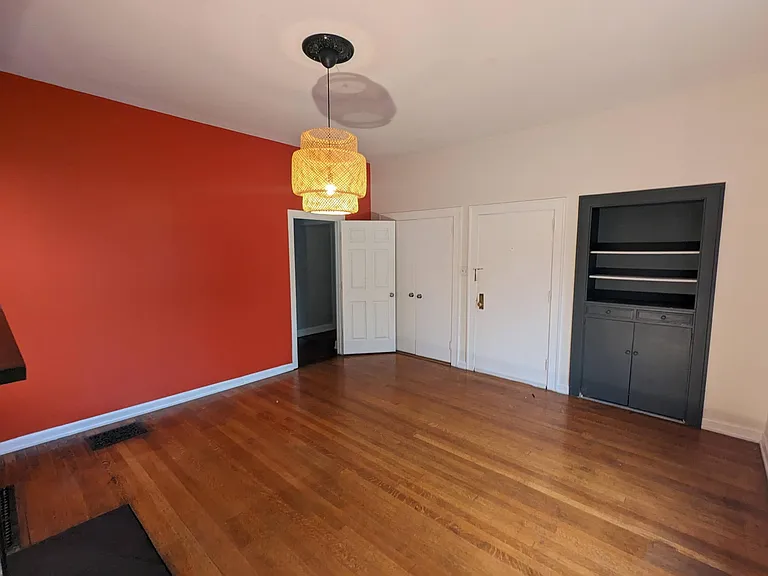 Beautiful front bedroom/dining room with original walnut hardwood floors, a non-functional fireplace, and a large closet and built-in bookshelf.