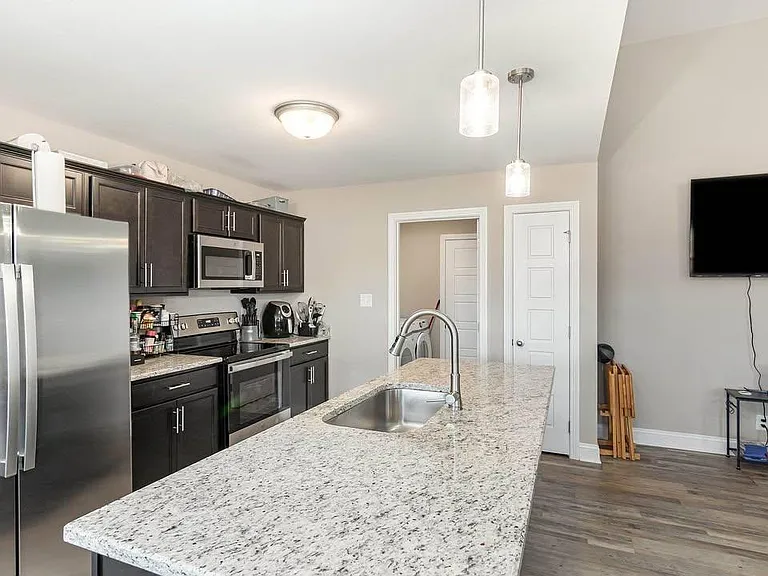 Spacious kitchen with a large granite island and undermount sink, plus stainless-steel appliances and ample cabinetry.