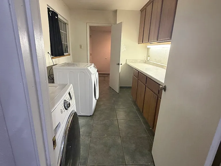 A spacious laundry and craft room with dual entrances offers exceptional functionality and organization, featuring additional built-in storage and plenty of workspace. The washer and dryer are included for added convenience.