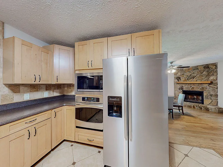 Kitchen with ample cabinet storage, tile backsplash, and stainless appliances including side-by-side fridge and wall oven.