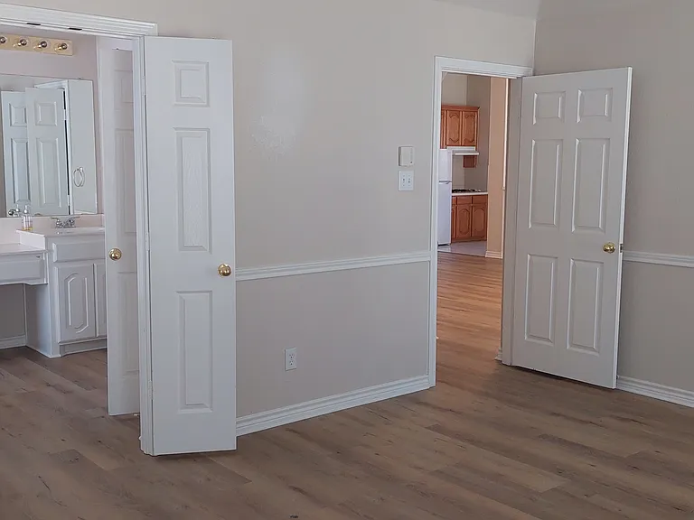 Master bedroom peaking into living area and master bath with attached walk-in closet. 7/20/2026