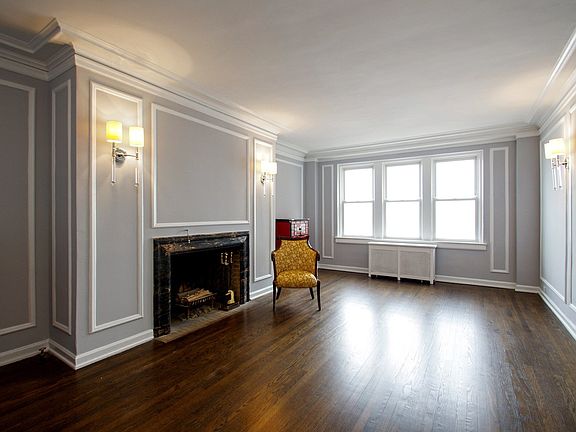 A Very grand space with a marble surround wood burning fireplace and 3 east facing windows to the st