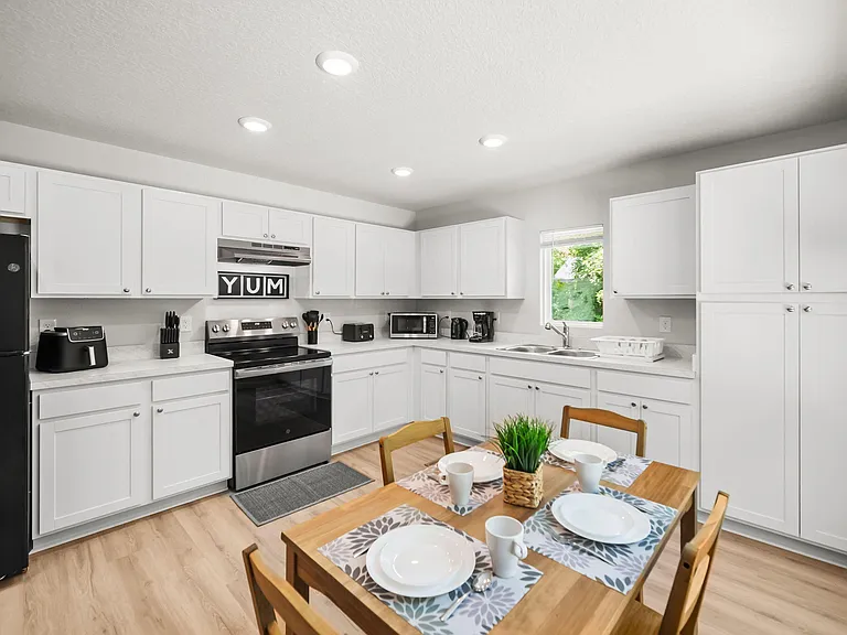Spacious eat-in kitchen with ample white cabinetry, generous counter space, and a full appliance suite plus double-basin sink