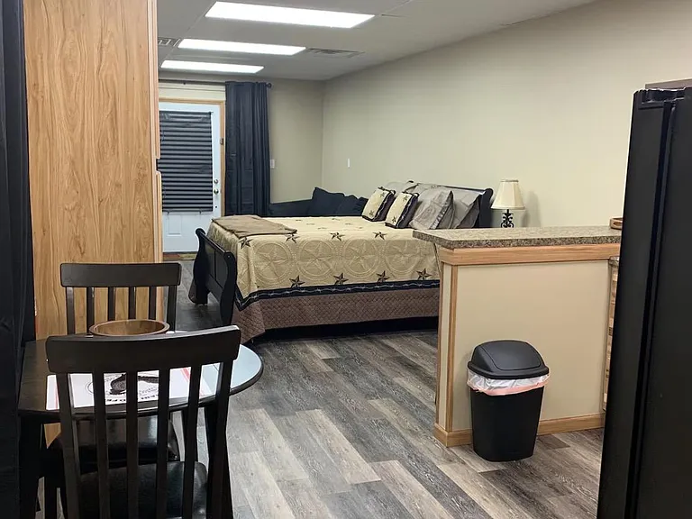 Furnished studio-style bedroom with a queen bed, small dining area, and convenient counter space for everyday use.