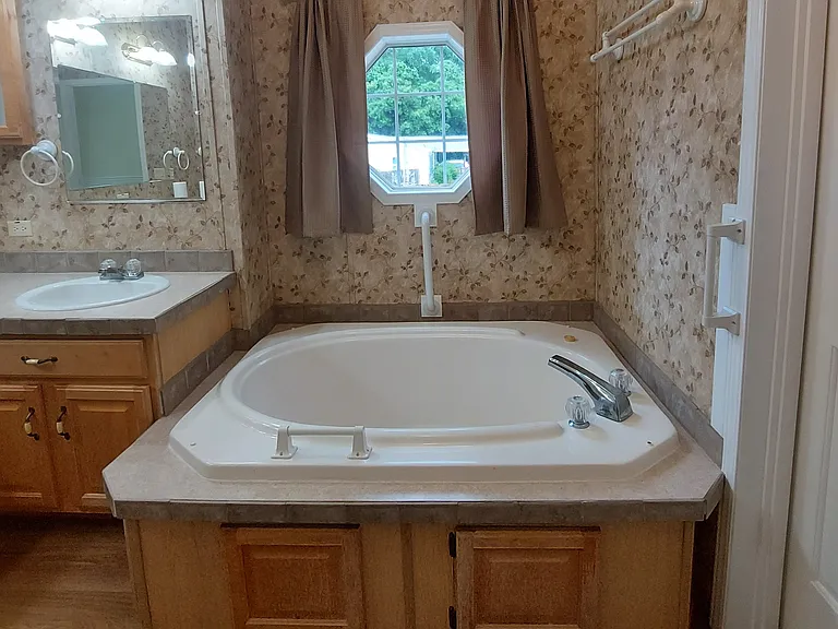 Both bathrooms have a beautiful, octagon window with curtains. Tub has ample, solid grab bars.