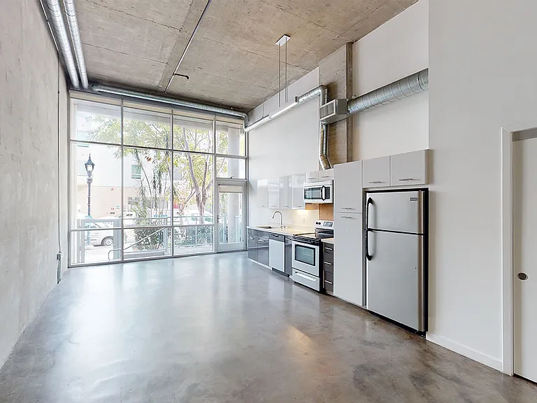 Apartment living room with polished concrete flooring and patio or balcony in select homes.