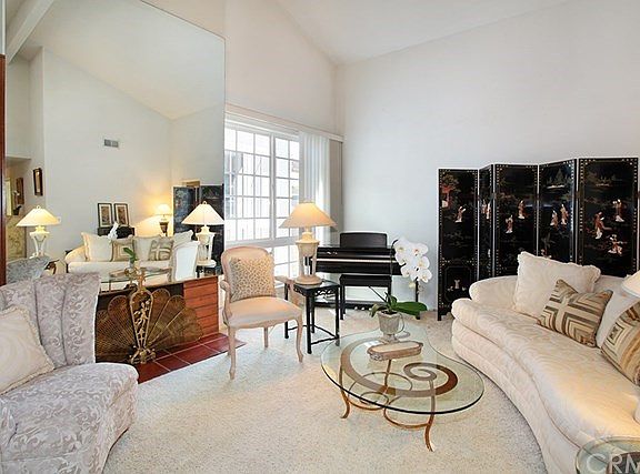 Living room view with cathedral ceiling and mirrored fireplace.