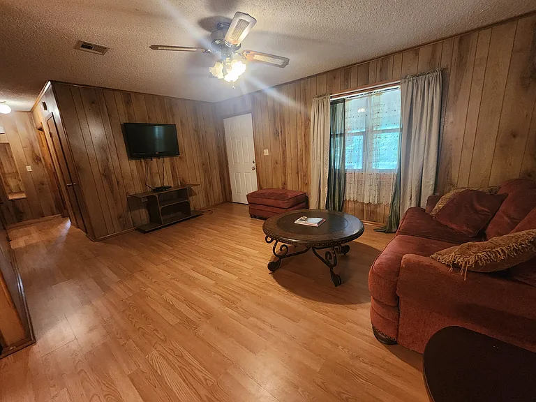 Partially furnished living room, ceiling fan, laminate hardwood floors, tv.