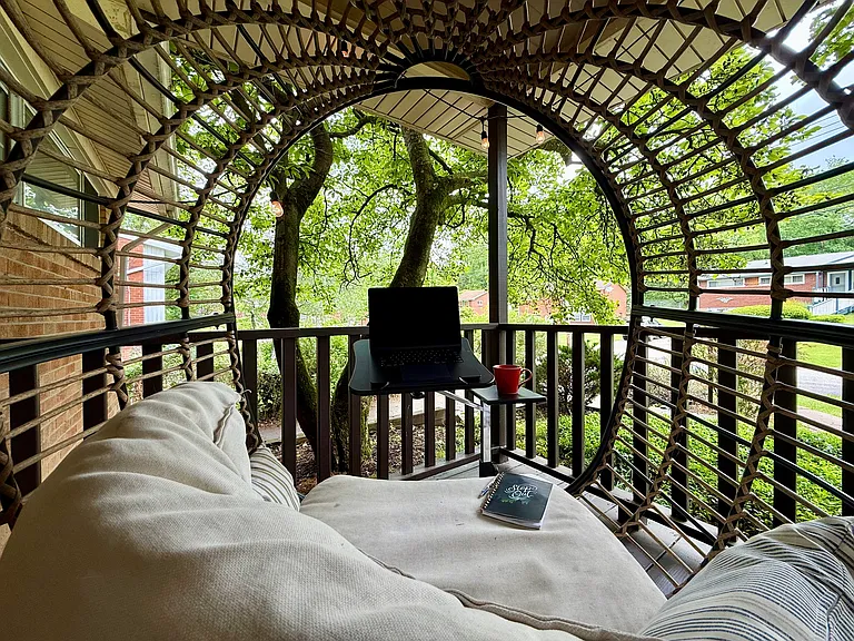 Covered porch work spot _ egg chair, screened by trees for privacy. Wi-Fi reaches outside, so remote work happens in fresh air