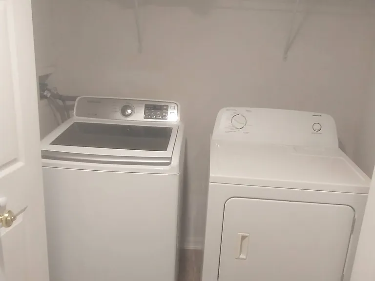 Washer and dryer in laundry closet located across from food pantry in hallway next to kitchen.