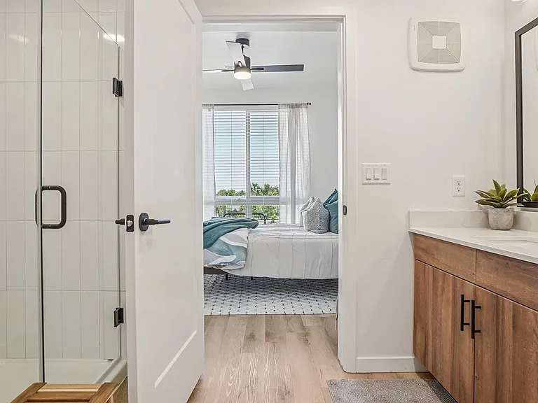 Refresh in a sleek bathroom featuring a glass-enclosed shower, wood-style vanity, matte black fixtures, and bright contemporary finishes.