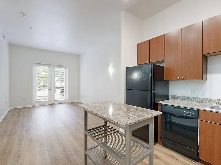 Apartment kitchen with stone counters and wood style floor.
