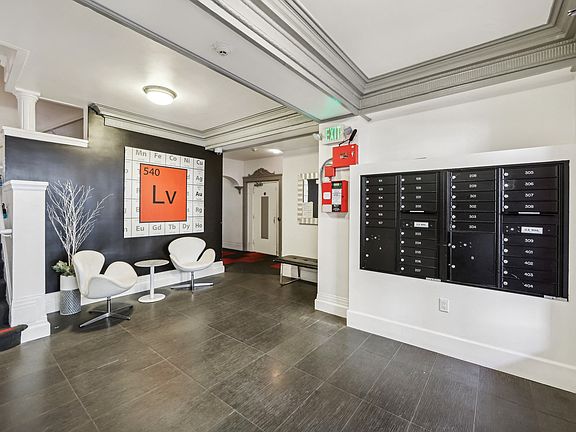 Apartment lobby with staircase, armchairs, and mailboxes