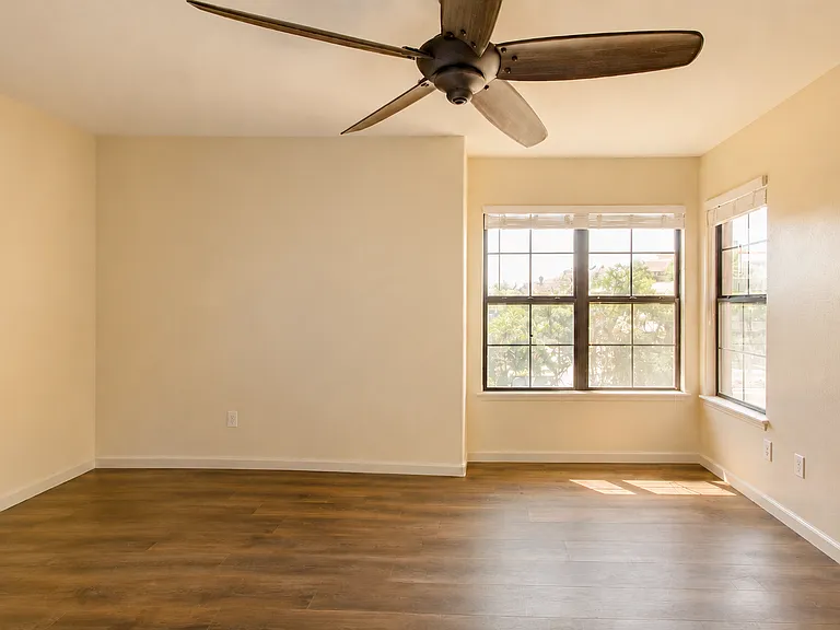 Primary bedroom with a walk-in closet, ceiling fan and ample lighting throughout