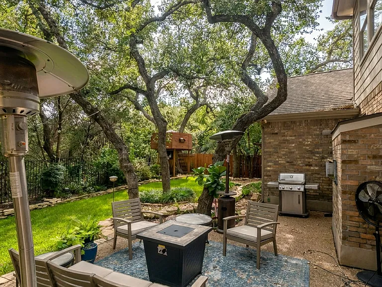 Brick-edged patio with fire-pit seating under the oaks