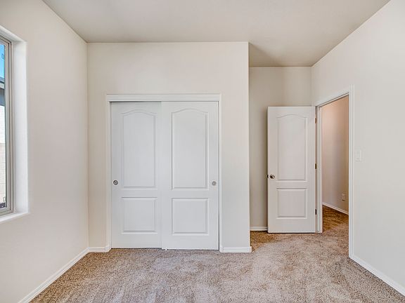 Guest bedroom with tan carpet and a closet with sliding doors.