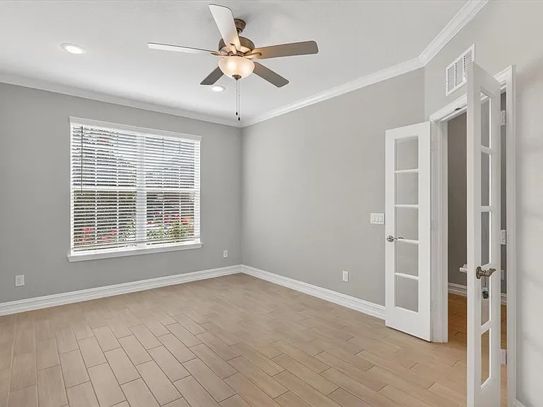 Room featuring light wood-finish plank flooring, a window with blinds, and a multi-blade ceiling fan with integrated lighting