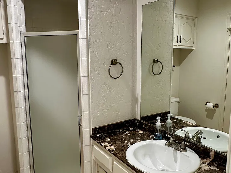 Bathroom featuring patterned tile flooring, vanity, toilet, and shower stall
