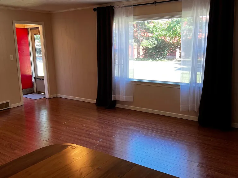 Photo of living room showing picture window and front door area with coat closet.