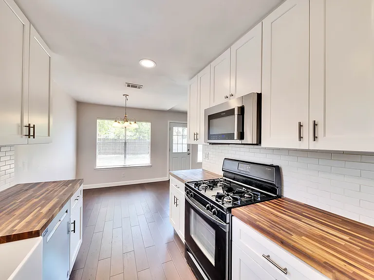 Modern Kitchen: featuring beautiful butcher block countertops, crisp white shaker style cabinets, and sleek stainless steel appliances.