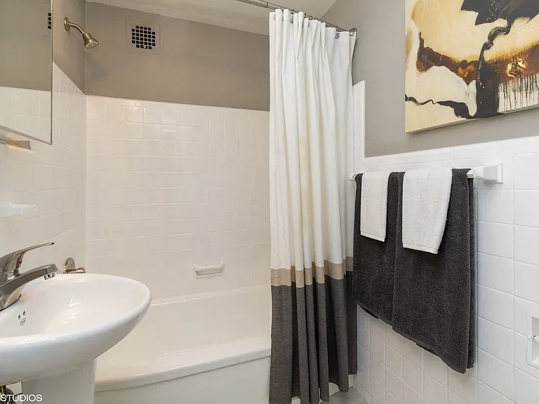 One bedroom model bathroom with sleek white tile